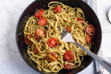 Pesto ve domatesle servis edilen spagetti.