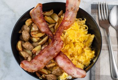 Çırpılmış yumurta ve patates kızartması. Üstü bocon ile servis edilmiş.