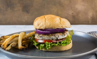 Kızarmış patatesle servis edilen tavuklu marul, domates ve soğanlı çörek.