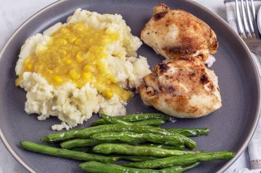 Patates püresiyle servis edilen tavuk budu kremalı mısır ve yanında sotelenmiş yeşil fasulye..