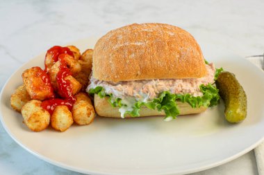 Ciabatta rulosunda marullu ton balığı salatası. Ketçaplı patates kroket ile servis ediliyor..