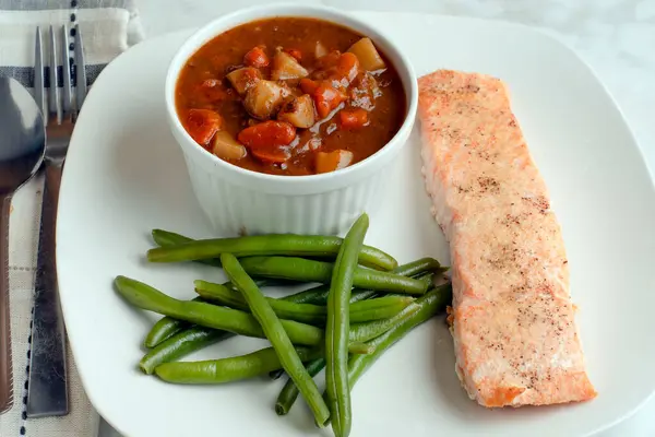biber, sarımsak ve soğan tuzlu yeşil fasulye ve sığır eti güveciyle servis edilmiş baharatlı somon üstü.
