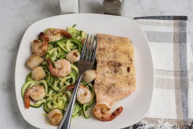  Baharatlı fırında somon, kabaklı şehriye, deniz tarağı ve karides ile servis edilir.