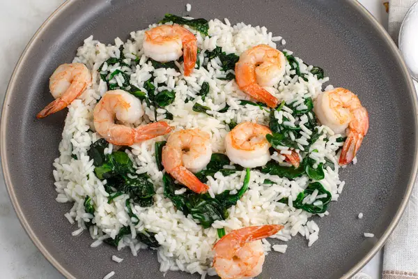 Sotelenmiş ıspanak ve tavada karides ile servis edilen beyaz pirinç..