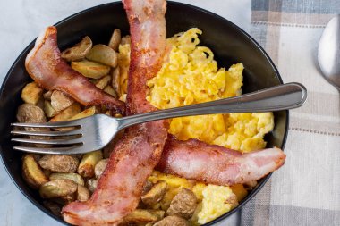 Çırpılmış yumurta ve patates kızartması. Üstü bocon ile servis edilmiş.