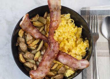 Çırpılmış yumurta ve patates kızartması. Üstü bocon ile servis edilmiş.