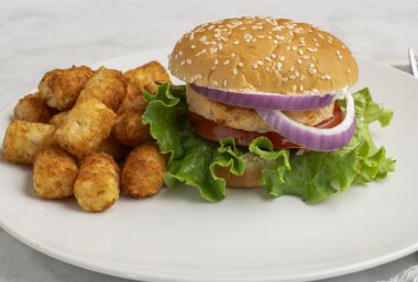 Salatalı somon burger, domates ve soğanlı patates kızartması..