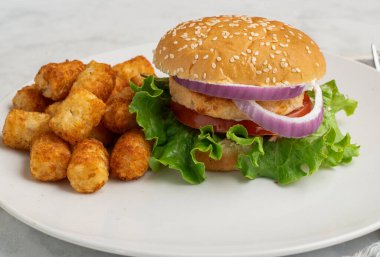 Salatalı somon burger, domates ve soğanlı patates kızartması..