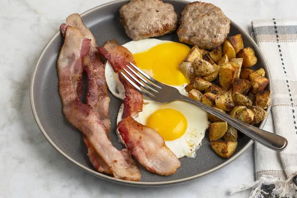  Domuz pastırmalı sahanda yumurta ve patates kızartmasıyla servis edilen sosisli börek.