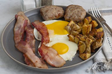  Domuz pastırmalı sahanda yumurta ve patates kızartmasıyla servis edilen sosisli börek.