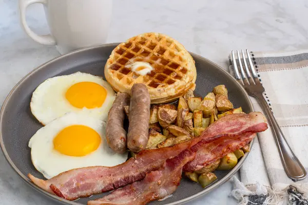 Erimiş tereyağlı kızarmış yumurta, domuz pastırması, sosis ve patates kızartması ile servis edilen şurup.