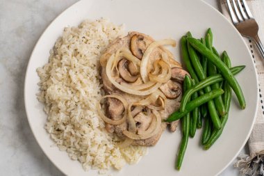 Pirinç ve yeşil fasulyeli sotelenmiş domuz pirzolası ve mantar.