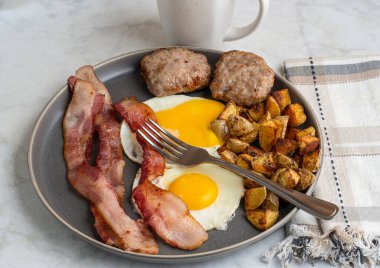  Domuz pastırmalı sahanda yumurta ve patates kızartmasıyla servis edilen sosisli börek.
