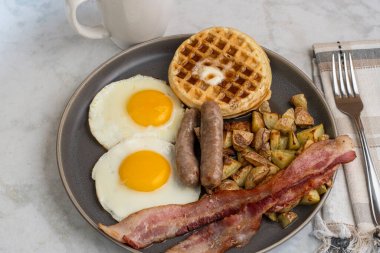 Erimiş tereyağlı kızarmış yumurta, domuz pastırması, sosis ve patates kızartması ile servis edilen şurup.