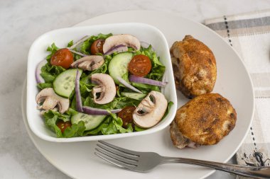 Kırmızı biberli tavuk budu, sarımsaklı tuz ve bahçe salatasıyla servis edilen soğan tuzu.