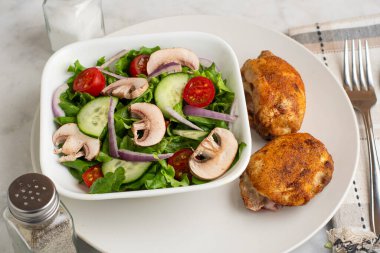 Kırmızı biberli tavuk budu, sarımsaklı tuz ve bahçe salatasıyla servis edilen soğan tuzu.