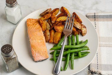 Patates püresi ve taze fasulye ile servis edilmiş fırında pişmiş somon.