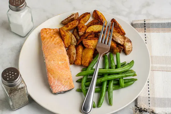 Patates püresi ve taze fasulye ile servis edilmiş fırında pişmiş somon.