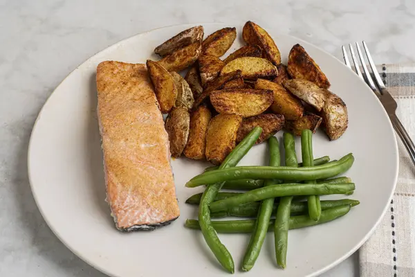 Patates püresi ve taze fasulye ile servis edilmiş fırında pişmiş somon.