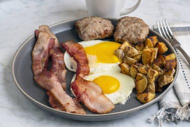  Domuz pastırmalı sahanda yumurta ve patates kızartmasıyla servis edilen sosisli börek.