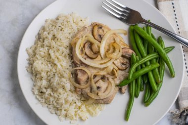 Pirinç ve yeşil fasulyeli sotelenmiş domuz pirzolası ve mantar.