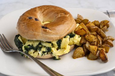 Yağda yumurta ve ıspanak yaban mersinli simit yanında da patates kızartması.