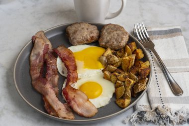  Domuz pastırmalı sahanda yumurta ve patates kızartmasıyla servis edilen sosisli börek.