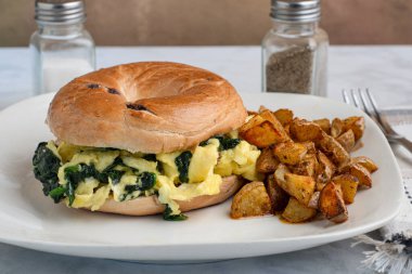 Yağda yumurta ve ıspanak yaban mersinli simit yanında da patates kızartması.