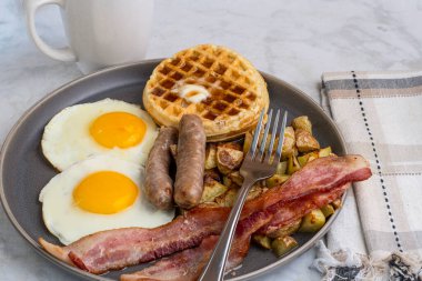 Erimiş tereyağlı kızarmış yumurta, domuz pastırması, sosis ve patates kızartması ile servis edilen şurup.