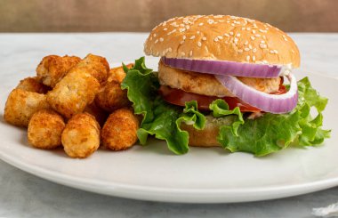 Salatalı somon burger, domates ve soğanlı patates kızartması..