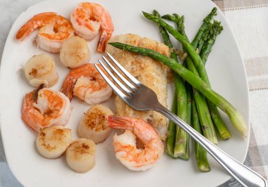 kuşkonmaz, istiridye ve karides ile servis edilen mezgit.