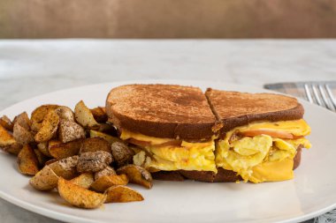 Çırpılmış yumurta ve Kanada pastırmalı peynirli sandviç erimiş kahvaltı sandviçi.