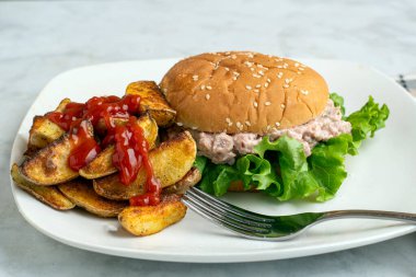 Susamlı salata, patates dilimleri ve ketçapla servis edilir.