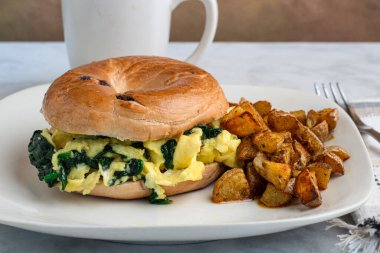 Yağda yumurta ve ıspanak yaban mersinli simit yanında da patates kızartması.