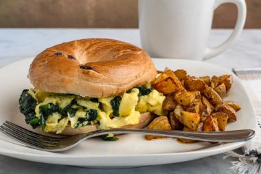 Yağda yumurta ve ıspanak yaban mersinli simit yanında da patates kızartması.