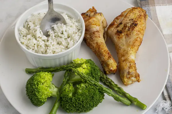 Brokoli ve aspaagusla servis edilen tavuk budu ve pilav.