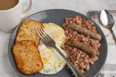 Kahvaltıda sosis ve mücver ile servis edilen mısır biftekli yumurta.