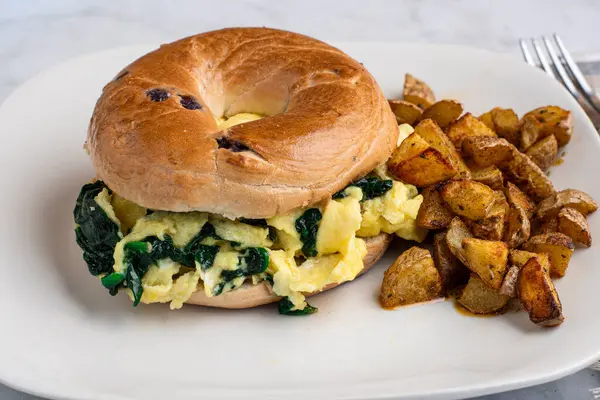 Yağda yumurta ve ıspanak yaban mersinli simit yanında da patates kızartması.