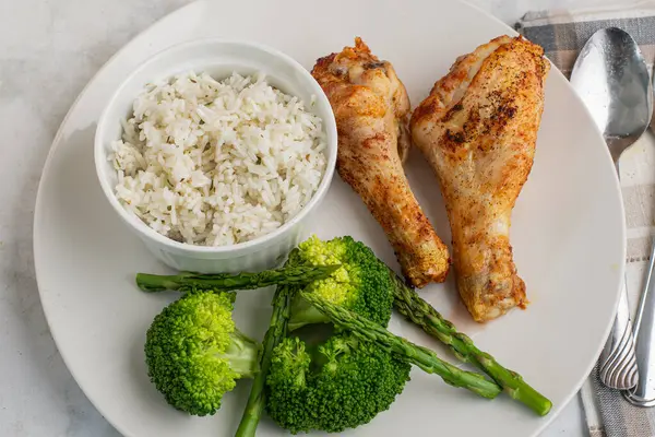 Brokoli ve aspaagusla servis edilen tavuk budu ve pilav.