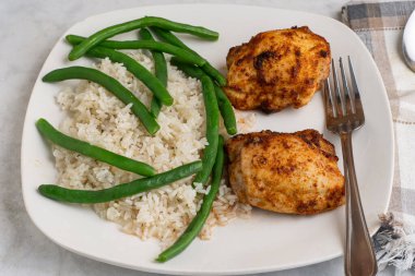  Pirinç ve yeşil fasulyeyle servis edilen tavuk butları.