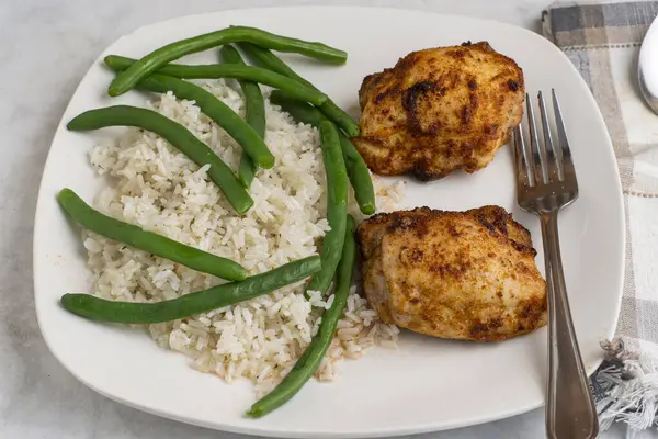  Pirinç ve yeşil fasulyeyle servis edilen tavuk butları.