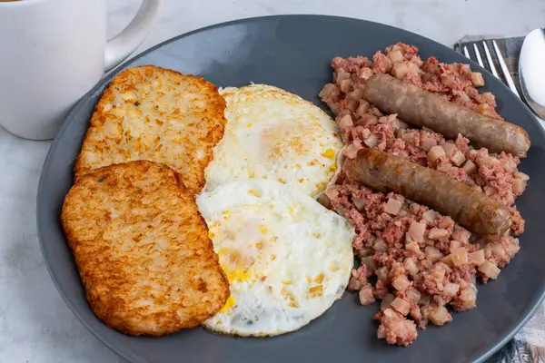 Kahvaltıda sosis ve mücver ile servis edilen mısır biftekli yumurta.