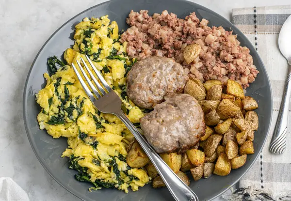 Çırpılmış yumurta, sosisli börek, patates kızartması ve mısır gevreği ile servis edilir.