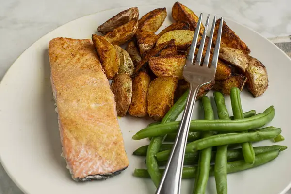 Patates püresi ve taze fasulye ile servis edilmiş fırında pişmiş somon.