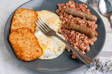 Kahvaltıda sosis ve mücver ile servis edilen mısır biftekli yumurta.