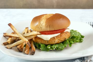 Marullu somon burger, domates ve patates kızartmasıyla servis edilen tarter sosu.