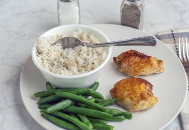 Pirinç ve yeşil fasulyeyle servis edilen tavuk butları.