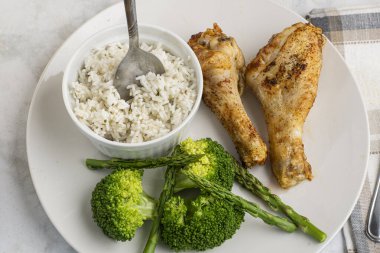 Brokoli ve aspaagusla servis edilen tavuk budu ve pilav.