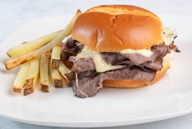 Kızarmış biftekli sandviç, erimiş peynir ve patates kızartması.