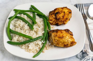  Pirinç ve yeşil fasulyeyle servis edilen tavuk butları.